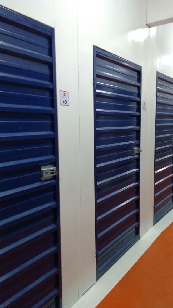 Corredor com boxes individuais numerados, portas com cadeado